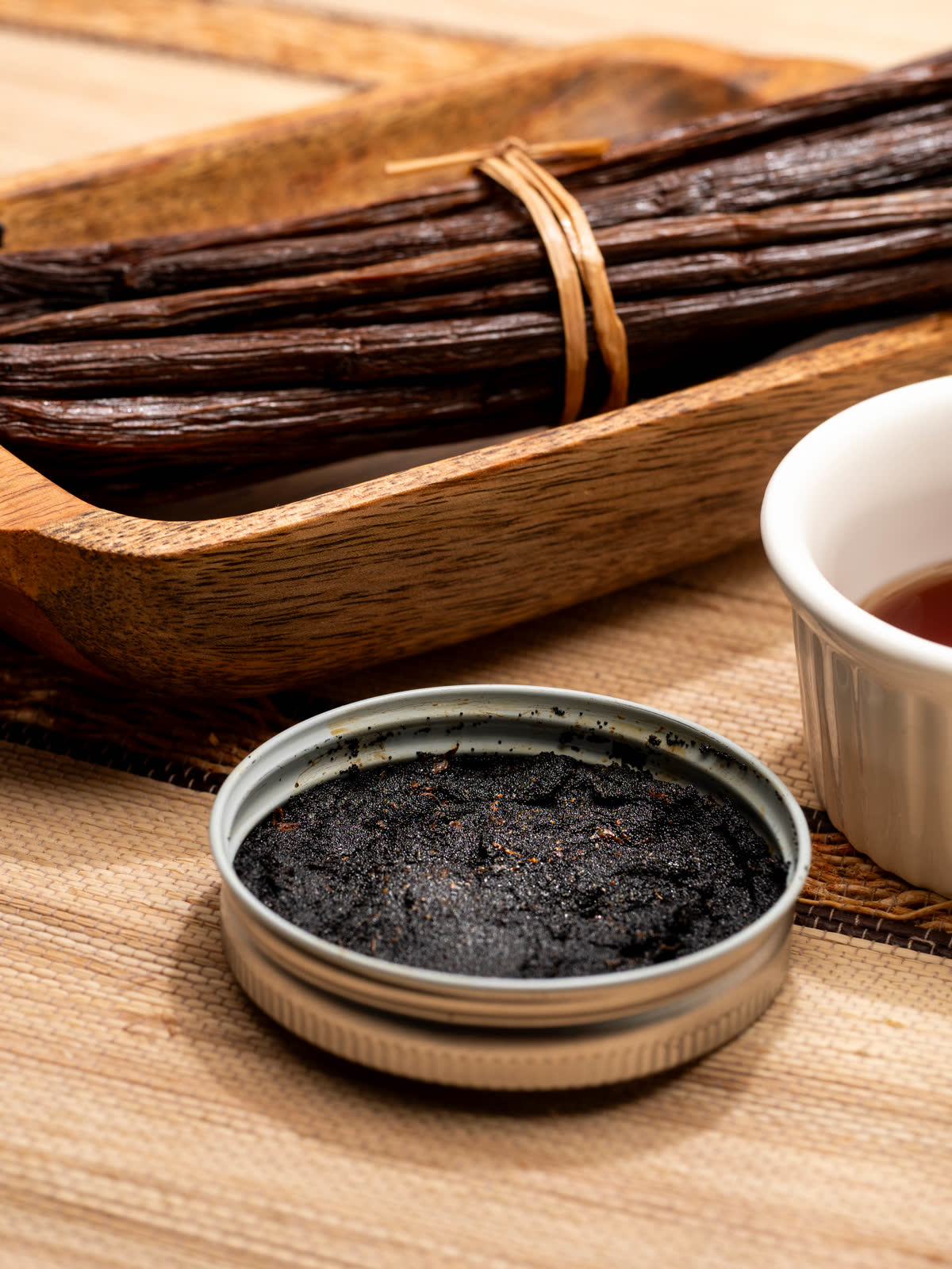 Madagascar vanilla bean paste in an open tin beside cured beans